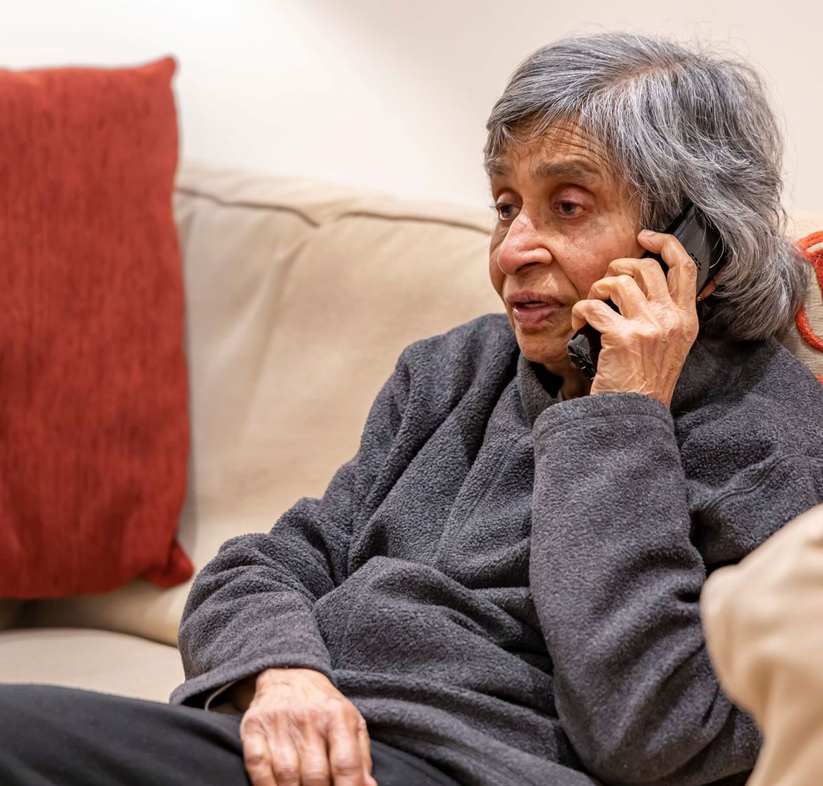 An Elderly Woman Sat On Her Sofa On The Phone Stock