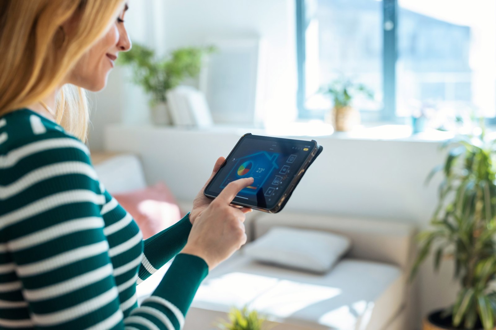 A woman looking at her tablet heating control